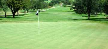 A view of green with narrow road on the left at San Antonio Country Club